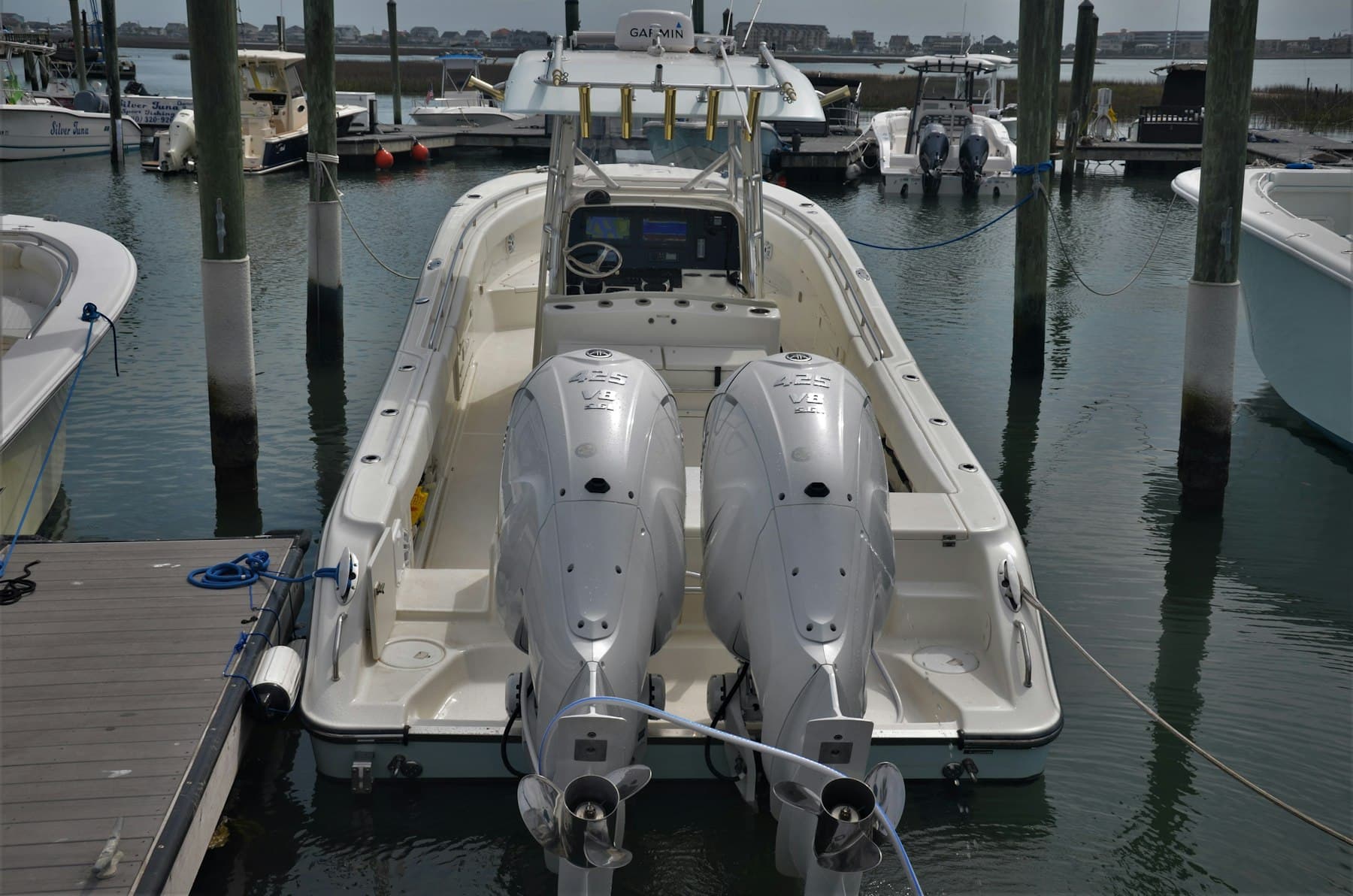 The center-console bay boat at the dock, T-top and electronics visible